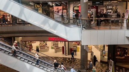 Interior de um Outlet com pessoas comprando em lojas