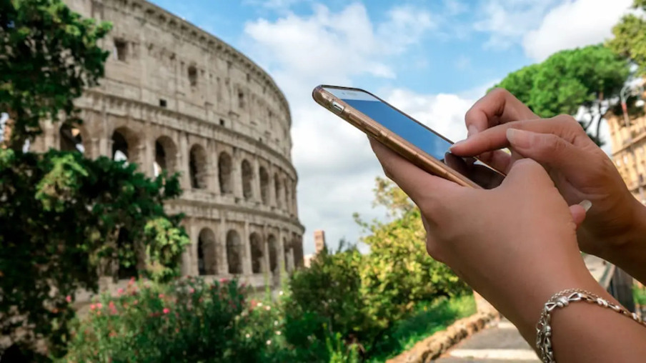 Usando o celular em frente ao Coliseu de Roma na Itália
