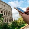 Usando o celular em frente ao Coliseu de Roma na Itália
