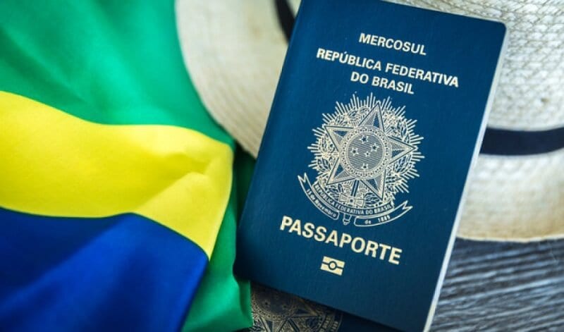 Passaporte entre a bandeira do Brasil e um chapéu ao lado