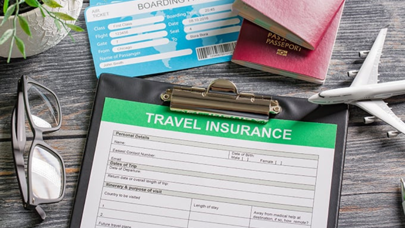Documento do seguro viagem para preencher em uma prancheta. Há outros documentos de viagem ao redor, como passaportes.