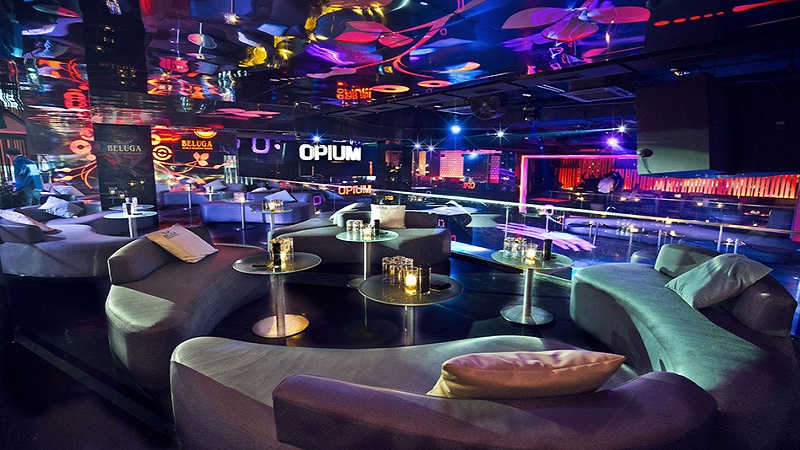 Interior da Balada Opium, sala com poltronas e mesas em meio às luzes coloridas do lugar. Nota-se o nome "Opium"