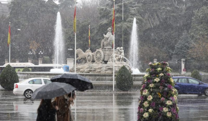 Pessoas andam com guarda-chuvas em Madri no inverno