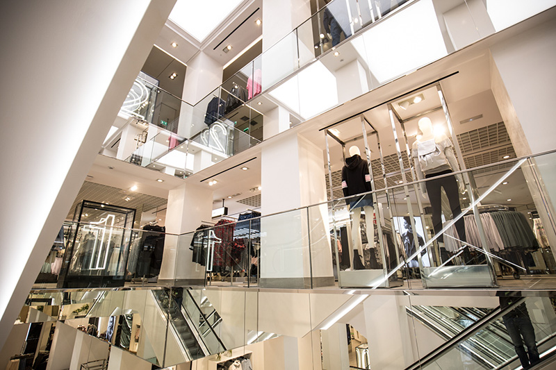Interior da Loja H&M, é possível notar escadas rolantes do prédio e vitrines da loja.