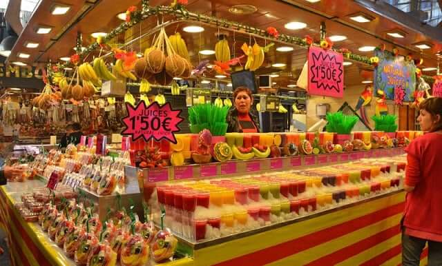 Interior do Mercado de La Boqueria de Barcelona. Mulher vende frutas e sucos em barraca no mercado.