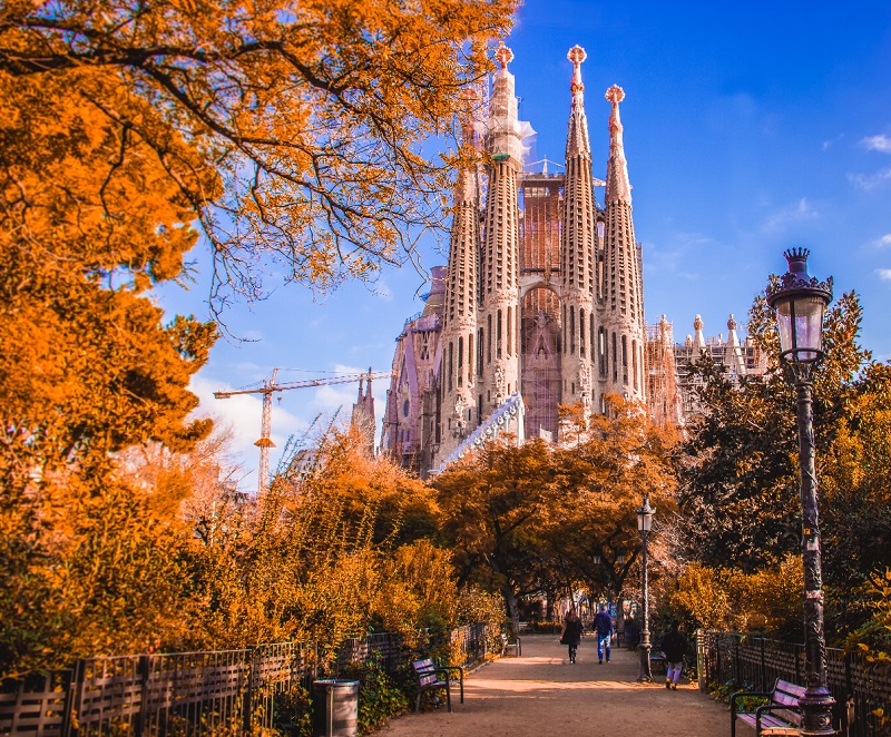 Catedral Sagrada Família em Barcelona no outono. Nota-se que as árvores estão alaranjadas por conta da estação.