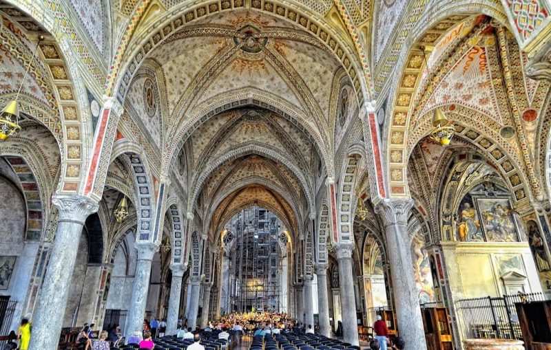 Interior da Igreja Santa Maria delle Grazie em Milão. Nota-se a estrutura composta por arcos e várias pessoas andam por lá.