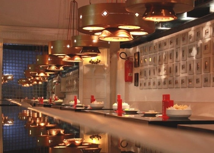 Interior do Bar Roialto em Milão. Nota-se luzes distribuídas no teto acompanhando as mesas que estão enfileiradas.