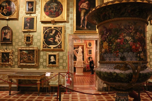 Interior da Galeria Palatina em Florença. Nota-se vários quadros e outras peças em exposição.