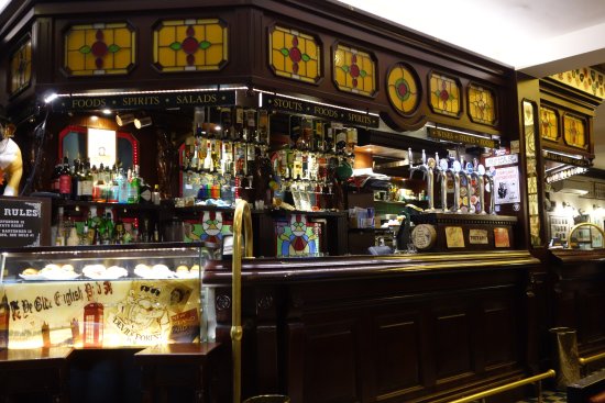 Interior do Devil’s Forest Pub em Veneza. Nota-se o balcão com muitas bebidas e espelhos na imagem.