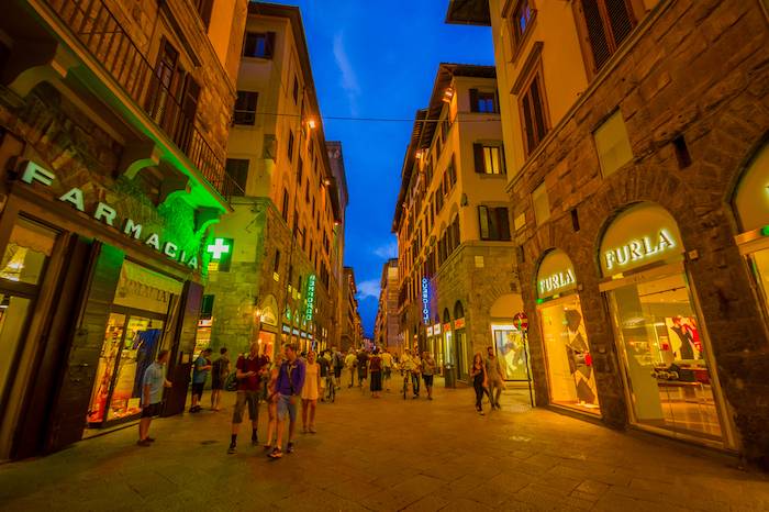 Pessoas andam por uma rua de Florença à noite.